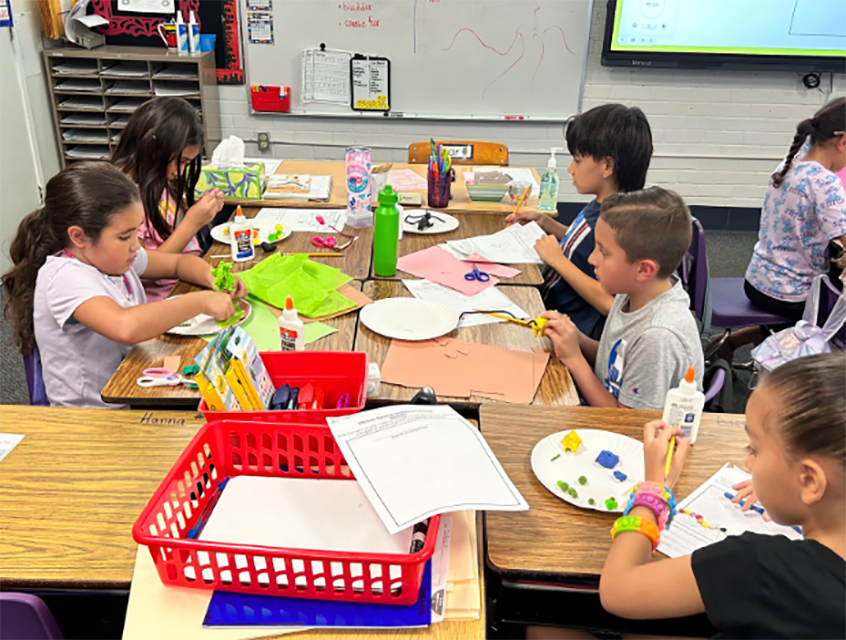 Students at a craft table creating desert creatures